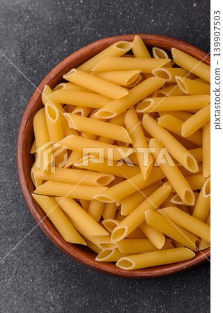 Italian uncooked dry penne regate pasta ready for cooking. Dry penne pasta Italian uncooked dry penne regate pasta ready for cooking. Dry penne pasta 139907503