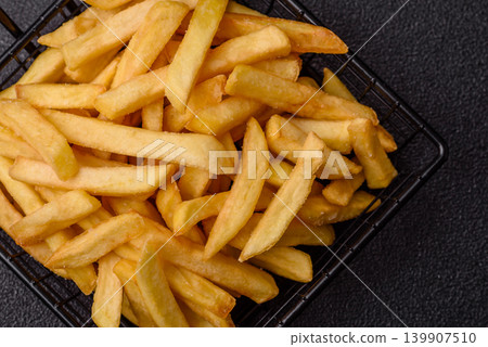 Crispy, fresh, golden French fries with salt, unhealthy takeaway food. French fries Crispy, fresh, golden French fries with salt, unhealthy takeaway food. French fries 139907510