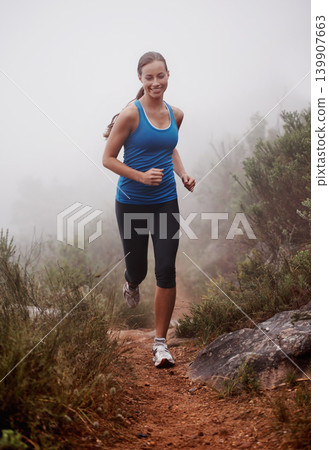 Woman, face and running in forest with fog for exercise, morning routine and workout with fitness and smile. Athlete, runner and person with happiness on mountain trail for wellness and healthy body Woman, face and running in forest with fog for exercise, morning routine and workout with fitness and smile. Athlete, runner and person with happiness on mountain trail for wellness and healthy body 139907663