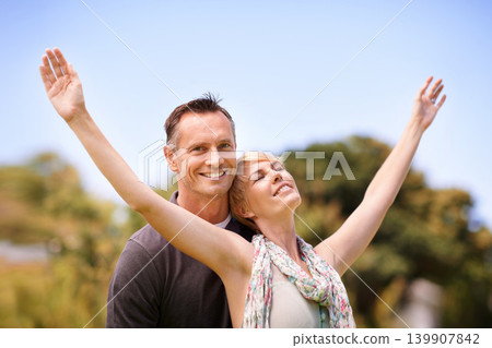 Couple, portrait and smile with love outdoors for honeymoon vacation, together and arms up for freedom. Man, woman and relationship with care for romance, marriage and support with happiness Couple, portrait and smile with love outdoors for honeymoon vacation, together and arms up for freedom. Man, woman and relationship with care for romance, marriage and support with happiness 139907842