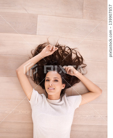 Woman, portrait and smile on floor for relax with top view, weekend break and confidence in apartment. Person, lying down and face with happiness in house on wooden flooring for fun and home 139907857