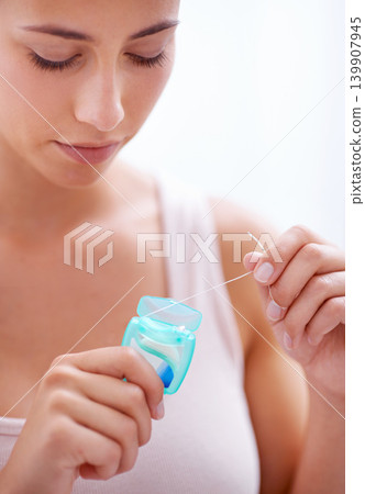 Dental, health and woman with floss in studio for health, wellness and oral hygiene routine. Treatment, mouth and young female person with product for cleaning teeth isolated by white background. Dental, health and woman with floss in studio for health, wellness and oral hygiene routine. Treatment, mouth and young female person with product for cleaning teeth isolated by white background. 139907945