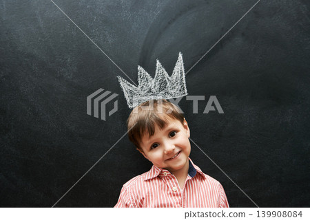 Little boy, portrait and crown on chalkboard in black background and smile for school in elementary class. Kid, happiness and education for development of learner, blackboard and cute drawing Little boy, portrait and crown on chalkboard in black background and smile for school in elementary class. Kid, happiness and education for development of learner, blackboard and cute drawing 139908084
