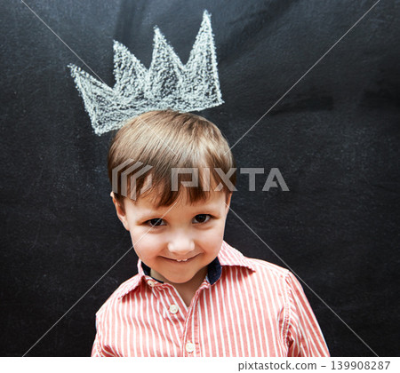 Little child, portrait and crown on blackboard from mischief of drawing by cute boy in classroom. Young kid, creative and artistic in preschool for elementary education, youth and clever student 139908287
