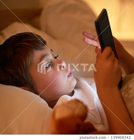 Boy, tablet and bed with night, learning and relaxing for social media or learning. Child, bedroom and connectivity for knowledge, youth and elearning or internet surfing at home with touchscreen 139908342