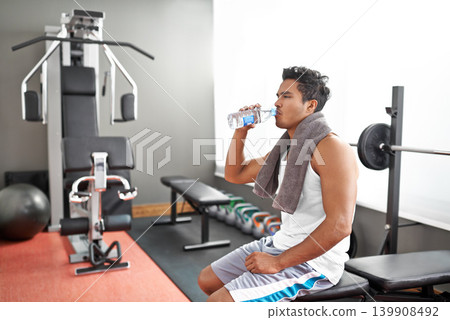 Fitness, gym and man drinking water for training, wellness or exercise recovery, break or resting. Workout, hydration and thirsty male athlete with sports drink after intense, cardio or bodybuilding Fitness, gym and man drinking water for training, wellness or exercise recovery, break or resting. Workout, hydration and thirsty male athlete with sports drink after intense, cardio or bodybuilding 139908492