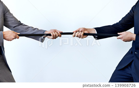 Business people, rope and tug of war for challenge, mission or strength of rivals on a blue studio background. Closeup of employees or colleagues hands pulling strong cable for competition on mockup 139908726