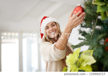 Woman, portrait and tree decoration for Christmas with smile, fun and excited in home. Festive, xmas decor and girl with ornament, Santa hat and happy December holiday event in apartment living room. 139908727