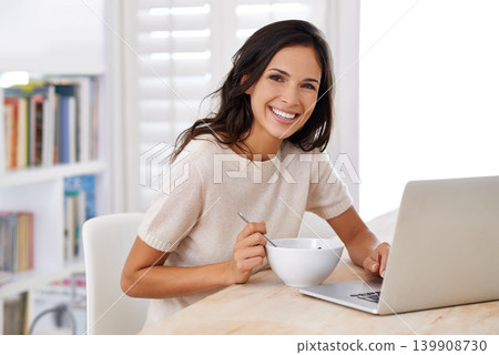 Woman, eating and cereal with laptop remote work from home in portrait with smile for healthy meal. Person, freelance writer and breakfast for diet, nutrition or computer at table in morning at house 139908730