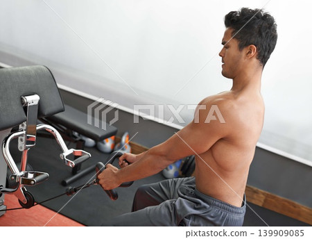 Fitness, rowing machine and shirtless man in gym for health, wellness or bodybuilding workout. Exercise, strong and focus with body of young bodybuilder athlete training on equipment for improvement Fitness, rowing machine and shirtless man in gym for health, wellness or bodybuilding workout. Exercise, strong and focus with body of young bodybuilder athlete training on equipment for improvement 139909085