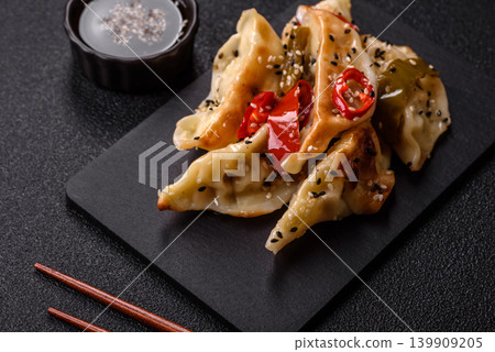 Gyoza, Chinese or Japanese meat dumplings, is an Asian food with hot peppers. Gyoza with meat Gyoza, Chinese or Japanese meat dumplings, is an Asian food with hot peppers. Gyoza with meat 139909205