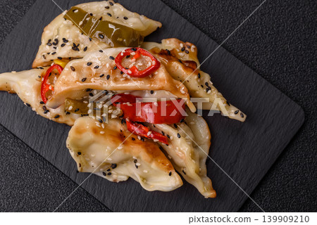 Gyoza, Chinese or Japanese meat dumplings, is an Asian food with hot peppers. Gyoza with meat Gyoza, Chinese or Japanese meat dumplings, is an Asian food with hot peppers. Gyoza with meat 139909210