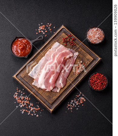 Raw fresh bacon slices with layers of meat or prosciutto with salt and spices. Raw bacon Raw fresh bacon slices with layers of meat or prosciutto with salt and spices. Raw bacon 139909826
