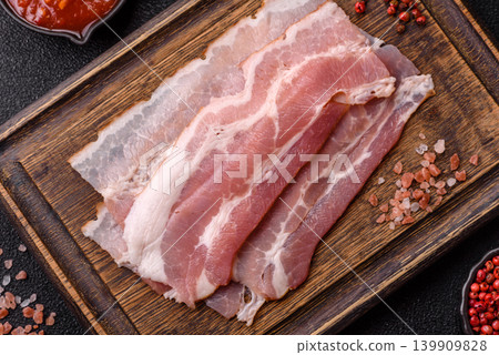 Raw fresh bacon slices with layers of meat or prosciutto with salt and spices. Raw bacon Raw fresh bacon slices with layers of meat or prosciutto with salt and spices. Raw bacon 139909828