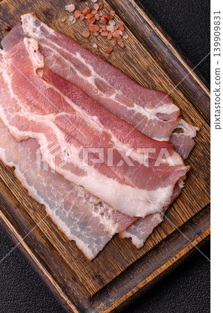 Raw fresh bacon slices with layers of meat or prosciutto with salt and spices. Raw bacon Raw fresh bacon slices with layers of meat or prosciutto with salt and spices. Raw bacon 139909831