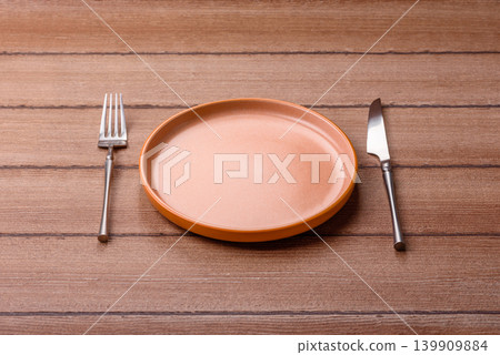 An empty ceramic round plate, kitchen utensils for a dinner table. An empty plate An empty ceramic round plate, kitchen utensils for a dinner table. An empty plate 139909884