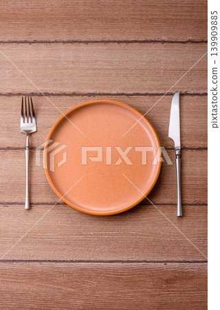An empty ceramic round plate, kitchen utensils for a dinner table. An empty plate 139909885