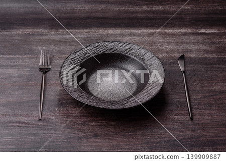 An empty ceramic round plate, kitchen utensils for a dinner table. An empty plate 139909887