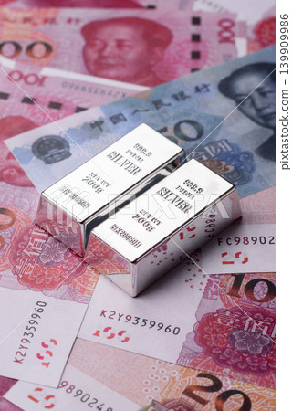 A silver bar, white metal against a backdrop of Chinese money, as a concept for the sales market A silver bar, white metal against a backdrop of Chinese money, as a concept for the sales market 139909986