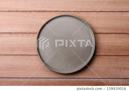 An empty ceramic round plate, kitchen utensils for a dinner table. An empty plate An empty ceramic round plate, kitchen utensils for a dinner table. An empty plate 139910016