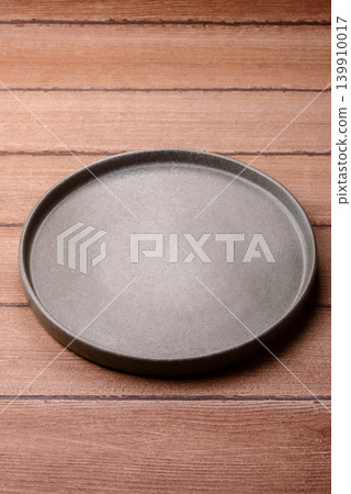 An empty ceramic round plate, kitchen utensils for a dinner table. An empty plate 139910017