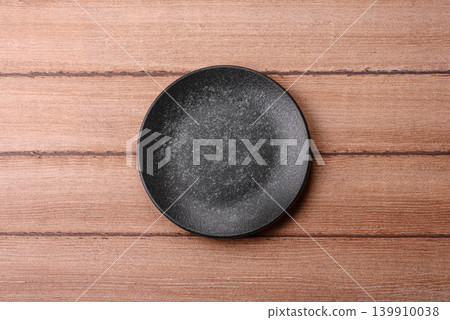 An empty ceramic round plate, kitchen utensils for a dinner table. An empty plate An empty ceramic round plate, kitchen utensils for a dinner table. An empty plate 139910038