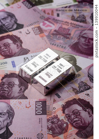 A silver bar, white metal against a backdrop of Mexican money, concept for the sales market A silver bar, white metal against a backdrop of Mexican money, concept for the sales market 139910044