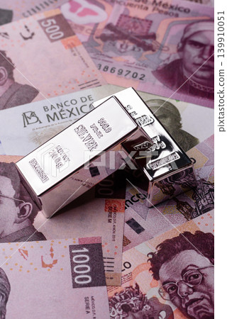 A silver bar, white metal against a backdrop of Mexican money, concept for the sales market 139910051