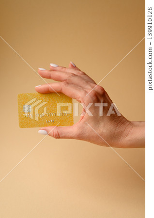 A credit card in a woman's hand as a conceptual backdrop for spending and shopping. A bank card A credit card in a woman's hand as a conceptual backdrop for spending and shopping. A bank card 139910128