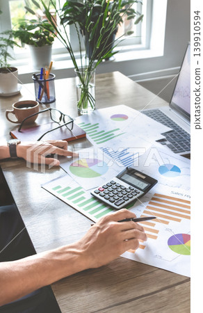Businessperson reviews business graphs on desk Businessperson reviews business graphs on desk 139910594