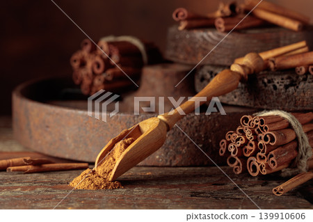 Wooden spoon with cinnamon powder and cinnamon sticks. Wooden spoon with cinnamon powder and cinnamon sticks. 139910606