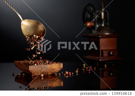 Black, red, white, and allspice peppercorns is poured in wooden dish. 139910618