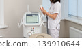 Female cosmetologist operating modern laser beauty equipment 139910644