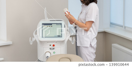 Female cosmetologist operating modern laser beauty equipment Female cosmetologist operating modern laser beauty equipment 139910644