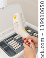 professional hands with red nails changing a cartridge on a white laser hair removal device 139910650