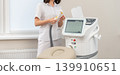 Female cosmetologist operating a modern laser hair removal machine 139910651