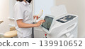 Professional cosmetologist operating a modern laser machine in a bright clinic. 139910652