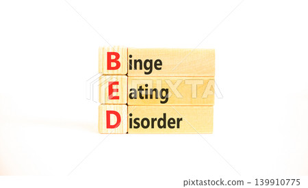 BED binge eating disorder symbol. Concept words BED binge eating disorder on beautiful wooden blocks. Beautiful white background. Medical BED binge eating disorder concept. Copy space. BED binge eating disorder symbol. Concept words BED binge eating disorder on beautiful wooden blocks. Beautiful white background. Medical BED binge eating disorder concept. Copy space. 139910775