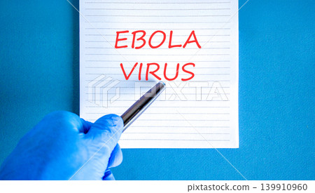 Ebola virus medical words symbol. Concept word Ebola virus on beautiful white note. Beautiful blue background. Doctor hand in blue medical glove. Black pen. Medical Ebola virus concept. Copy space. Ebola virus medical words symbol. Concept word Ebola virus on beautiful white note. Beautiful blue background. Doctor hand in blue medical glove. Black pen. Medical Ebola virus concept. Copy space. 139910960