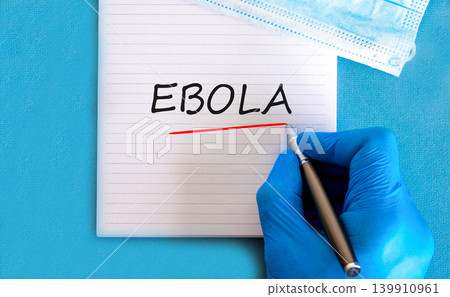 Ebola virus medical words symbol. Concept word Ebola on beautiful white note. Beautiful blue background. Doctor hand in blue medical glove. Medical mask. Medical Ebola virus concept. Copy space. Ebola virus medical words symbol. Concept word Ebola on beautiful white note. Beautiful blue background. Doctor hand in blue medical glove. Medical mask. Medical Ebola virus concept. Copy space. 139910961