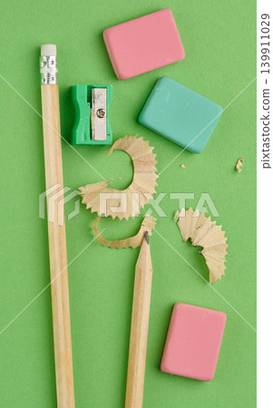 Green plastic pencil sharpener, sharp wooden pencil and figured shavings on green background, top view, preparation for drawing concept Green plastic pencil sharpener, sharp wooden pencil and figured shavings on green background, top view, preparation for drawing concept 139911029