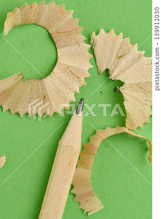 Close-up of a sharpened pencil surrounded by swirls of wood shavings on a green paper background Close-up of a sharpened pencil surrounded by swirls of wood shavings on a green paper background 139911030