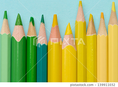 Close-up of a row of green and yellow wooden pencils on a blue background Close-up of a row of green and yellow wooden pencils on a blue background 139911032