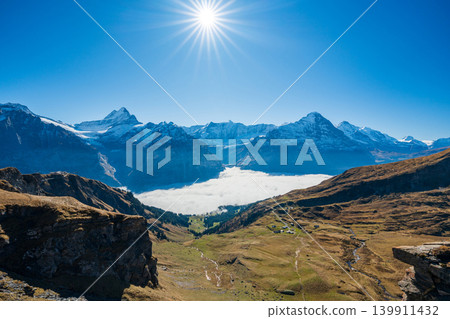 A breathtaking panoramic view of the sea of clouds and autumn valleys stretching out at the foot of the Eiger and Schreckhorn peaks. Grindelwald, Bern Canton, S. A breathtaking panoramic view of the sea of clouds and autumn valleys stretching out at the foot of the Eiger and Schreckhorn peaks. Grindelwald, Bern Canton, S. 139911432