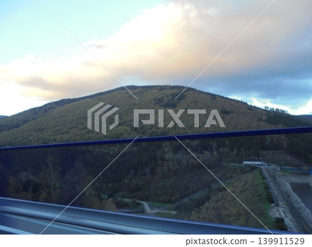 Cloud over autumn forested hill in Beskydy, road balustrade obstructing view Cloud over autumn forested hill in Beskydy, road balustrade obstructing view 139911529