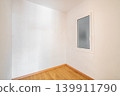 Empty room with white walls and a wooden floor. A single window is present, allowing natural light to enter the space 139911790