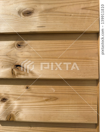 Close up of natural textured wooden planks featuring distinct grain patterns and organic knots creating a warm rustic background for design projects Close up of natural textured wooden planks featuring distinct grain patterns and organic knots creating a warm rustic background for design projects 139911810
