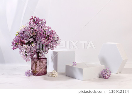 Aesthetically pleasing cosmetic display case with floral decor for showcasing beauty products. Abstract floral arrangement with podiums and lilac blossoms. Minimalistic, modern design. Aesthetically pleasing cosmetic display case with floral decor for showcasing beauty products. Abstract floral arrangement with podiums and lilac blossoms. Minimalistic, modern design. 139912124