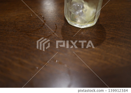 A cold drink in the summer. The condensation from the cold glass wet the wooden table. A cold drink in the summer. The condensation from the cold glass wet the wooden table. 139912384