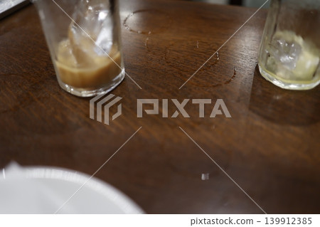 夏日裡的一杯冰飲。冰冷的玻璃杯壁上凝結的水汽打濕了木桌。 夏日裡的一杯冰飲。冰冷的玻璃杯壁上凝結的水汽打濕了木桌。 139912385